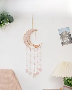 Detailed view of moon-shaped pink crystal tree of life dreamcatcher hanging on a white wall