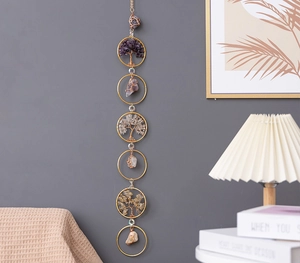 Close-up of handmade crystal suncatcher tree of life wall hanging on a gray wall