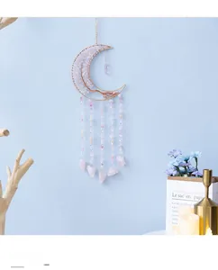 Macro detail of moon-shaped dream catcher with pink crystal stones and beaded tassels