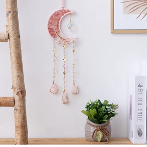 Detail of moon-shaped dream catcher with pink crystal tree of life and hanging stones