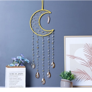 Detail of yellow crescent moon dreamcatcher with crystal droplets on blue wall