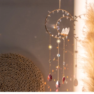 Detail of moon suncatcher with raw crystal cluster and rainbow prisms in sunlight
