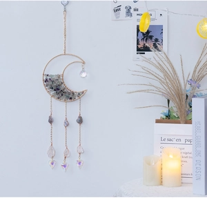Detailed golden moon suncatcher with purple crystals and laser heart pendant on white wall