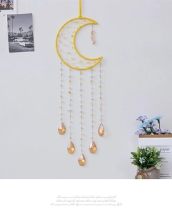 Detail of moon-shaped yellow dreamcatcher with crystal pendants and beaded mesh