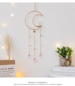 Macro view of moon-shaped sun catcher featuring raw crystals and gold metal chains
