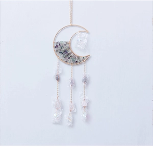 Detail of moon-shaped crystal suncatcher with golden crescent frame and fluorite stones