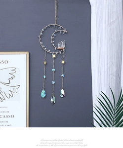 Detail of crescent moon crystal suncatcher with golden metal frame and hanging prisms