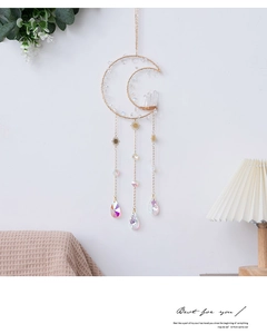 Detail of moon-shaped crystal suncatcher with golden frame and iridescent drops