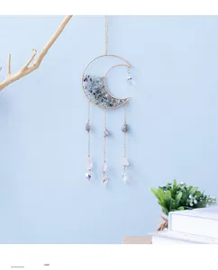 Detail of moon-shaped crystal suncatcher with purple stones and hanging heart prism