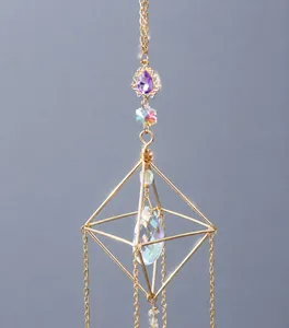 Detalle de un atrapasol dorado con gemas púrpuras y un gran colgante de cristal brillante
