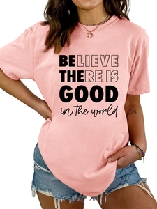 Détail du texte 'BELIEVE THERE IS GOOD' imprimé sur un t-shirt rose en coton