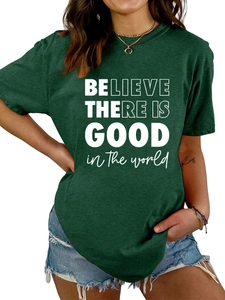 Détail d'un t-shirt vert foncé avec l'inscription 'Believe There Is Good' en blanc