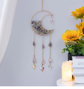 Detail of moon-shaped suncatcher with purple crystal stones and heart prisms