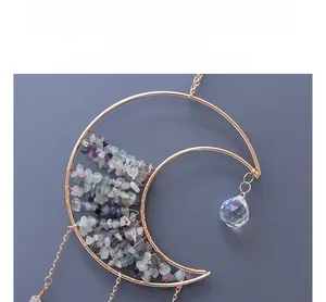 Detail of moon-shaped suncatcher with gold metal frame, fluorite stones and crystal prism
