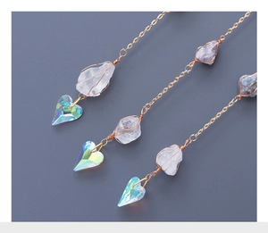 Detail of gold chain suncatcher with white quartz crystal and iridescent heart prism