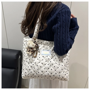 Detalle del bolso tote acolchado blanco con corazones y un bonito colgante de peluche