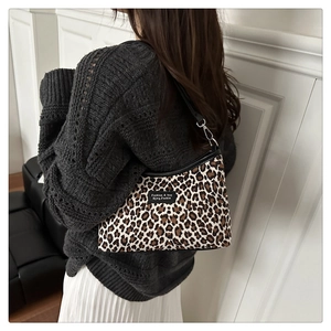 Detail of leopard print underarm bag worn with a grey sweater and white pleated skirt