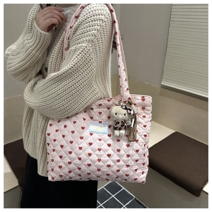 Detalle de bolso tote rosa acolchado con corazones rojos y un lindo colgante de peluche