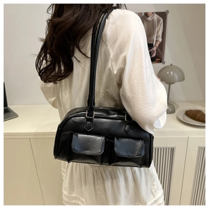 Detail view of a retro black bowling shoulder bag with two functional front flap pockets
