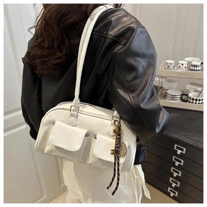 Detail of white leather underarm bag featuring dual pockets and tennis racket charm