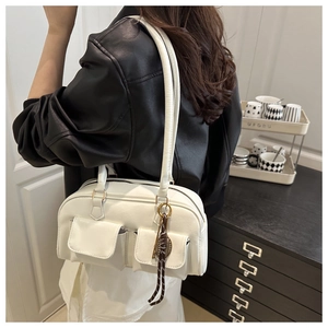 Close-up of white Boston bag with dual flap pockets and woven rope detail on black leather jacket