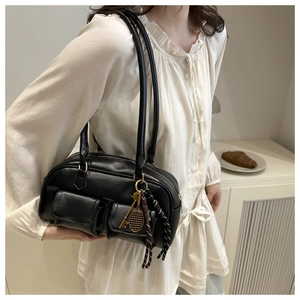 Detail of black faux leather shoulder bag with small exterior pockets and tennis charm