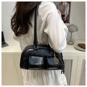 Detail view of black leather shoulder bag featuring side pockets and gold tennis racket charm