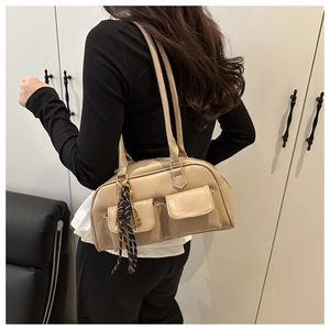 Detail of minimalist beige faux leather shoulder bag with decorative scarf and gold pendant