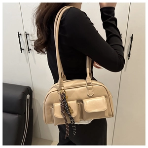 Detail of beige shoulder bag with dual front pockets and textured rope knot charm