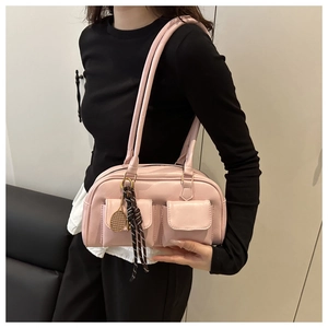 Detail of pink leather underarm bag featuring utility pockets and a gold tennis racket charm