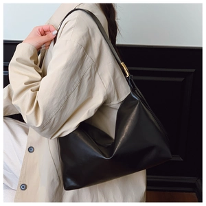 Detail of minimalist black hobo tote with a distinct gold metallic buckle on shoulder strap