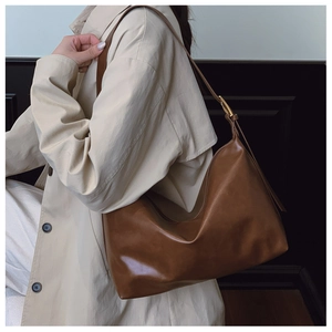 Detail of a brown leather hobo shoulder bag with golden metal buckle on wide strap