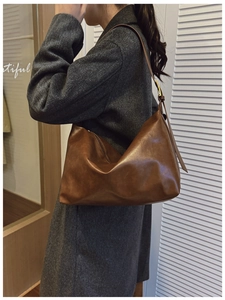 Detail of a brown leather hobo shoulder bag with adjustable strap and gold metal buckle