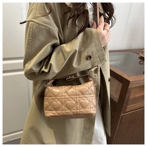 Quilted heart pattern bucket bag in beige leather styled on a trench coat model