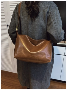 Brown leather shoulder bag styled with a grey wool coat for a chic winter commute look