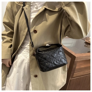 Detail of heart-shaped quilted leather bucket bag with gold metal clasp on a model