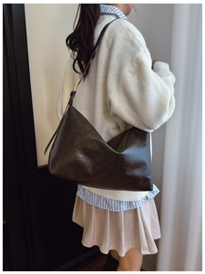 Detail of a large dark brown faux leather hobo bag with adjustable strap on a model