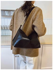 Detail of adjustable wide shoulder strap and gold hardware on large black tote bag