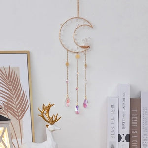 Golden moon suncatcher with crystal clusters and rainbow pendants on a white wall