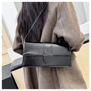 Detailed back view of a black retro textured leather baguette bag on a brown blazer outfit