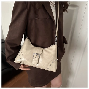 Detailed close-up of beige tote bag with silver studs and adjustable shoulder strap