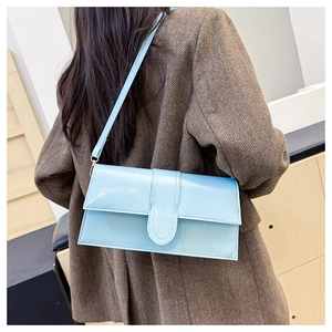 Detail of light blue glossy leather shoulder bag with flap closure and metal buckle