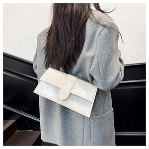 Detail of glossy beige shoulder bag featuring reflective finish and minimal design