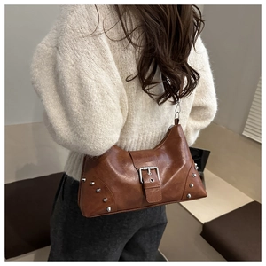 Detail view of brown shell bag with silver rivets and metal buckle on leather strap