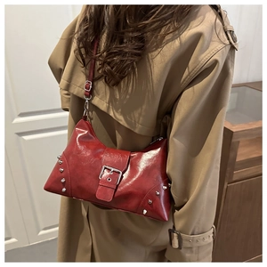 Détails d'un sac bandoulière en cuir rouge brillant avec des rivets argentés