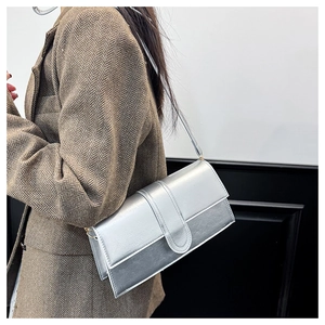 Detail of a metallic silver baguette bag worn over a brown herringbone wool blazer