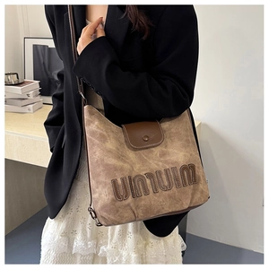 Detail of vintage canvas tote with leather trim and contrast 3D letter embroidery