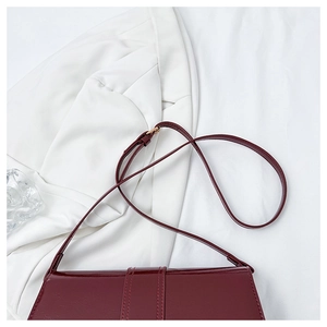 Close-up of wine red polished leather shoulder bag with gold metal buckle detail