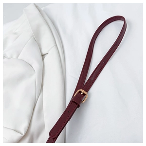 Detail of burgundy leather strap with golden buckle and fine stitching on white fabric