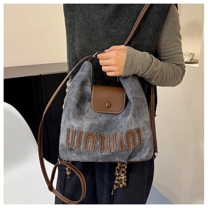 Detail of vintage denim tote with brown leather flap and leopard print scarf accessory